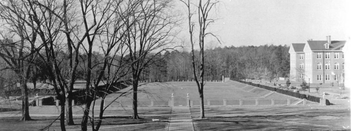 Black and white photo of the Sunken Garden with white picket fence in front and Blair Hall in the distance