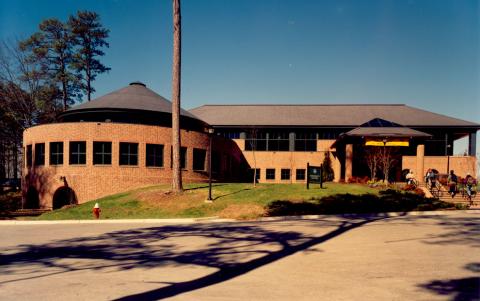 Front facade of the Sadler Center with a round extension on the left and road in front