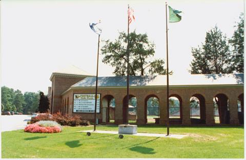 View of the entrance to Zable Stadium with parking to the left, and brick arches revealing the field on the right