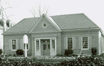 Single story brick building with round garden in front