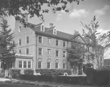 Three story brick building with brick fenced yard