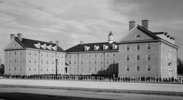 Black and white photo of three three story brick buildings oriented in a U shape with central yard