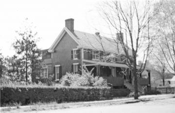 Two story brick colonial house with covered front porch and dark shutters