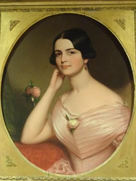Round gold framed portrait of Cynthia Beverly Tucker, seated and wearing a pink dress