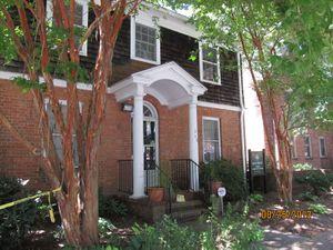 Two story brick house with gambrel roof and two white columns at the entry