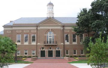 Front facade of the two story brick Miller building with gardens on either side