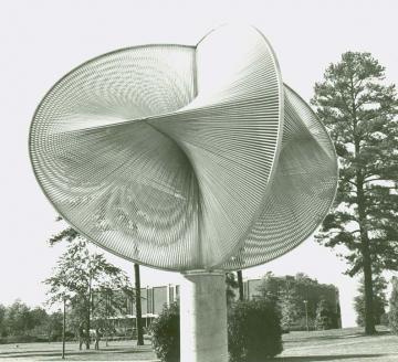 Modern sculpture in silver featuring waves that seem to merge into each other